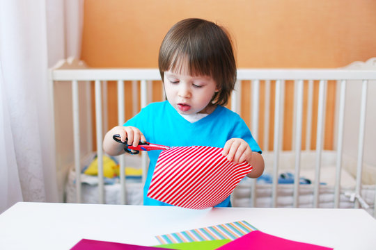 lovely toddler boy with scissors cutting paper