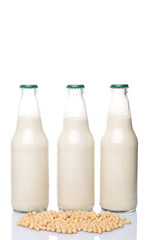 Soybean and bottles of soybean milk over white background