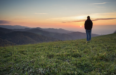 man standing on hill in black forest at sunset