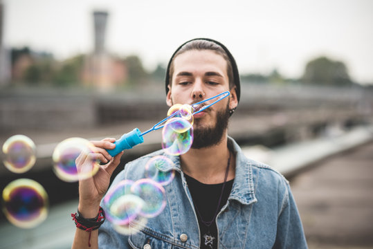 young handsome bearded hipster man blowing bubbles soap