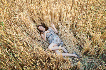 girl in rye field. girl lies on an ear of wheat.