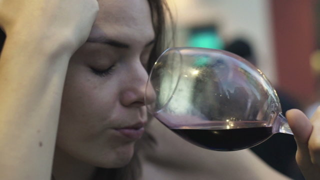 Close up of drunk woman drinking red wine in bar 
