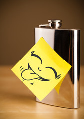 Post-it note with smiley face sticked on hip flask