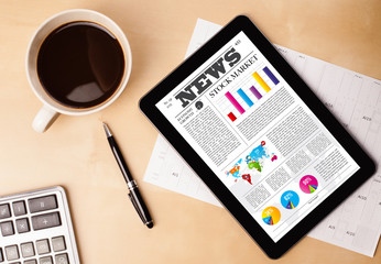 Tablet pc shows news on screen with a cup of coffee on a desk