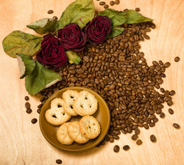 dry red roses and cookies on coffee seeds