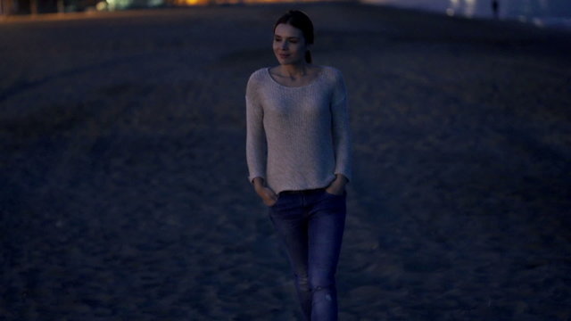 Pretty, happy woman walking on beach at night