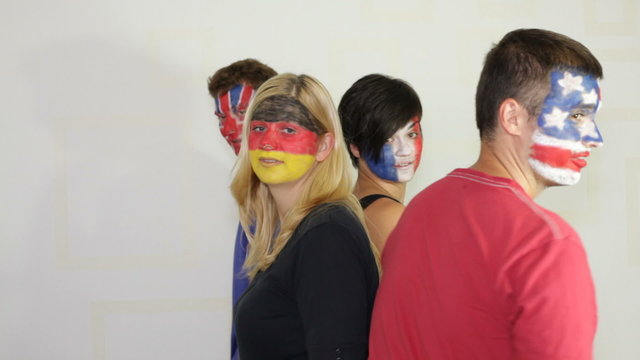 People with flags painted on faces dancing and smiling.