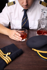 The pilot in uniform drinking alcohol