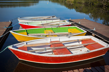 Obraz premium Floating Color Wooden Boats with Paddles in a Lake