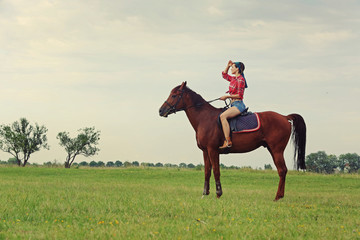 Fototapeta na wymiar Young woman with red plaid shirt riding horse outdoor