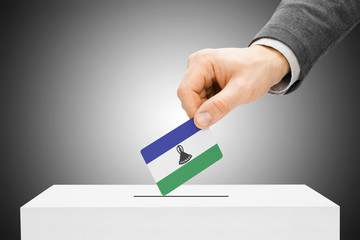 Voting concept - Male inserting flag into ballot box - Lesotho
