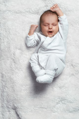 infant yawning stretches on  white fur