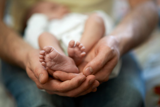 Dad holds in his hands  small baby foot