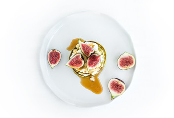 Marrow pancakes with fresh figs, honey and goat cheese on a whit