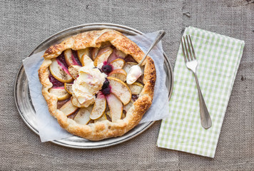 Apple and berry galette on a metal dish over a sackcloth surface