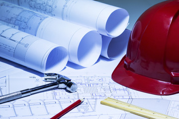 Construction plans with red helmet and drawing tools