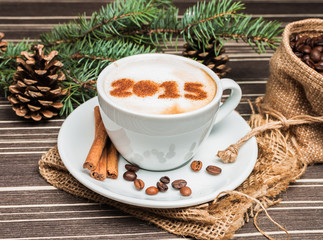 cup of cappuccino near Christmas tree with cones