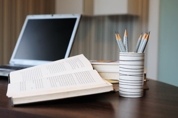 work table with computer notebook,pencil, book in a home