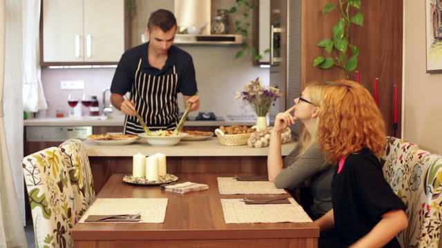 Man preparing salad for women at home