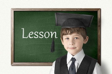 Cheerful little boy on blackboard. Looking at camera