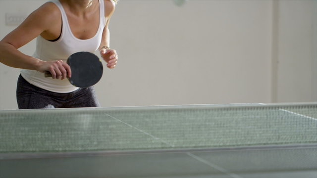 Attractive woman playing table tennis indoors in slow motion