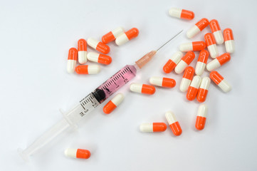Syringe and capsules on white background.