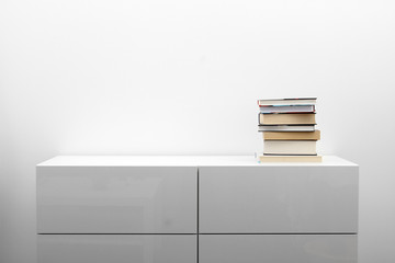 white commode with stack of books in bright minimalism interior