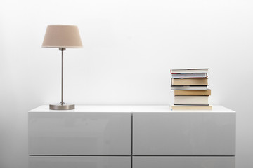 white commode with lamp and books in bright minimalism interior