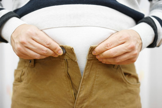 man is unable to close his pants because of gaining weight