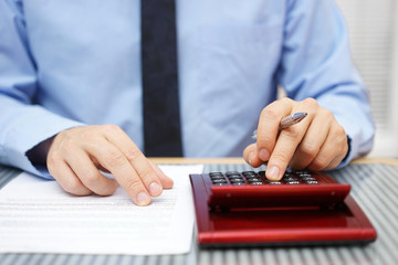 Businessman calculating  and checking articles of agreement