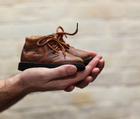 Dirty hands holding a pair of old childrens shoes