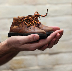 Dirty hands holding a pair of old childrens shoes