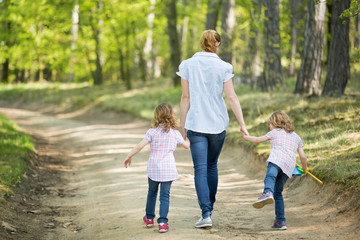 Fototapeta premium Mutter mit Zwillingen geht im Wald spazieren