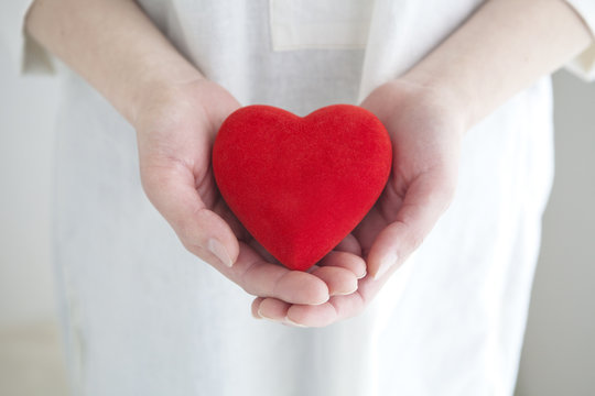 赤いハートを持つ女性の手