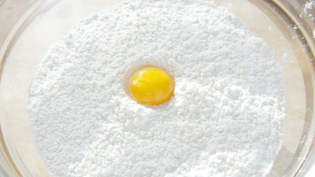 Egg falling in flour bowl