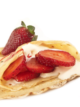 Crepes  con fresas y nata sobre fondo un blanco liso Vista de frente y de cerca. Copy space. Formato vertical