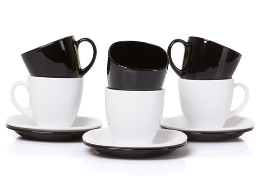Black on white cups with stack plates on white background.