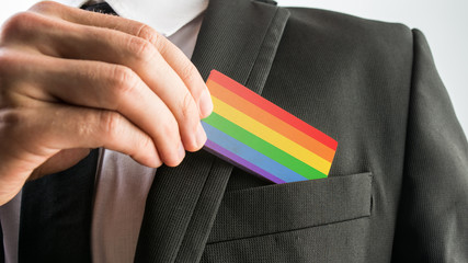 Man withdrawing a wooden card painted as the gay pride flag