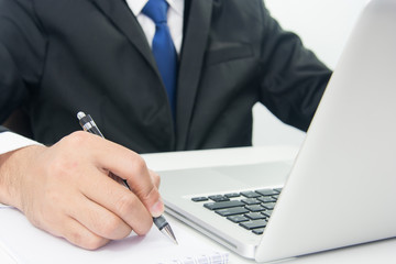 Businessman Sitting Working on Laptop and write note
