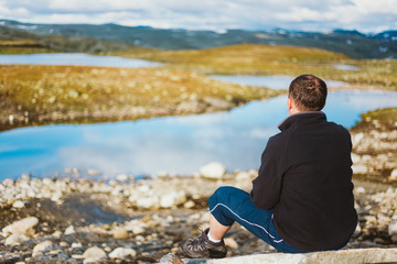 Fototapeta premium Man Sitting On Stone In Norwegian Mountains