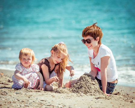 mother and daughters playing in the sand