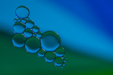 blue and green drops of oil and air bubbles on the water