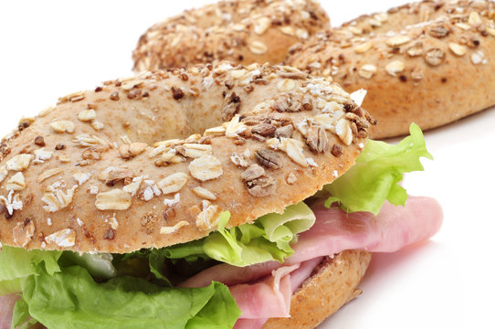 brown bagel filled with ham and lettuce mix