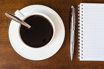 Notebook and a pen with cup of the coffee