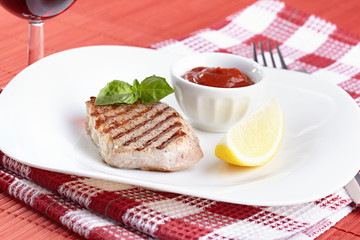 Grilled steak with tomato sauce and a lemon
