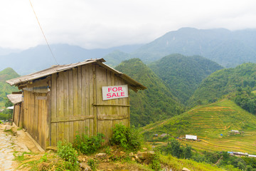 Wooden house with a sign for sale