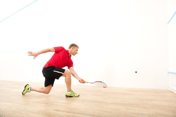 squash player hiting ball in squash court.