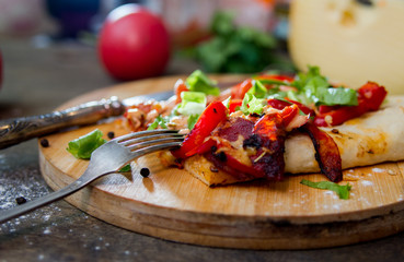 slice of pizza with peppers, bacon and herbs on a wooden board