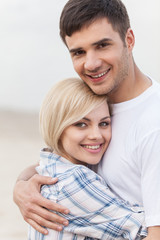 Attractive young couple standing on beach at summer