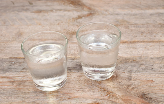 Two glasses of vodka on wooden table